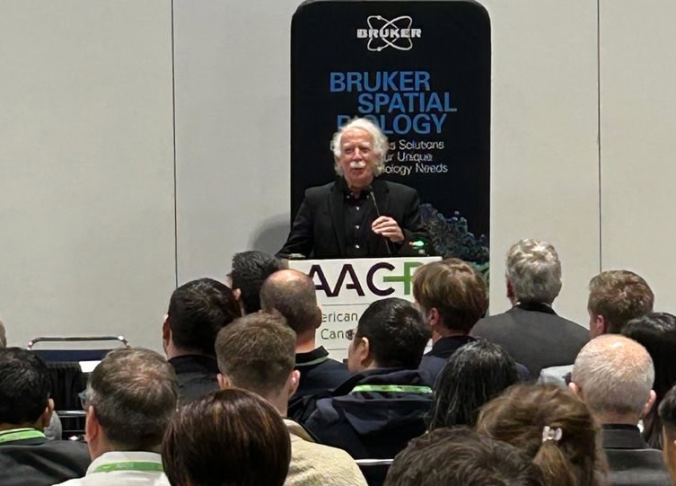 Joe Beechem speaking from behind a podium in front of a group of people.