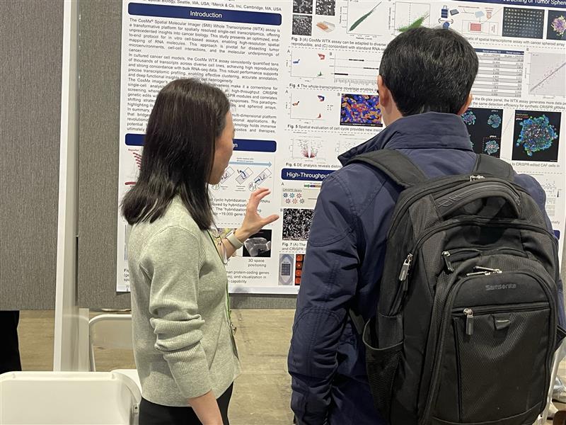 Two people standing in front of a poster.