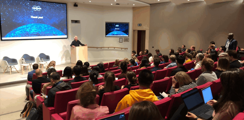 Joe Beechem giving presentation to hall full of people